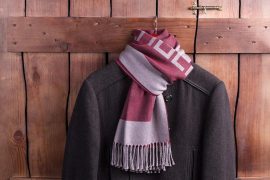 Winter men's coat with a warm scarf. Men's clothes hanging on a wooden fence.